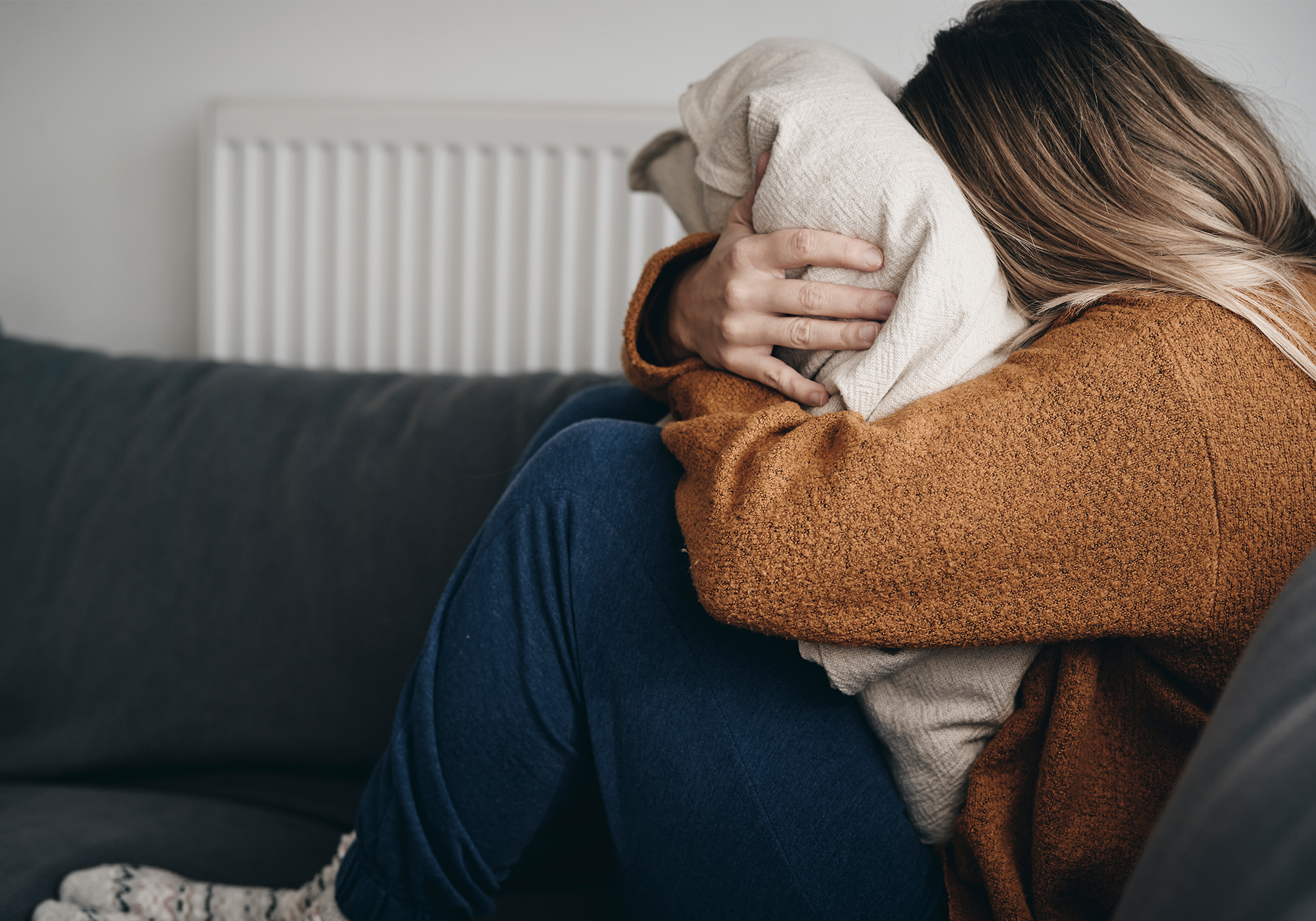 Junge Frau hält sich die Hände vors Gesicht, wirkt überfordert oder nachdenklich.